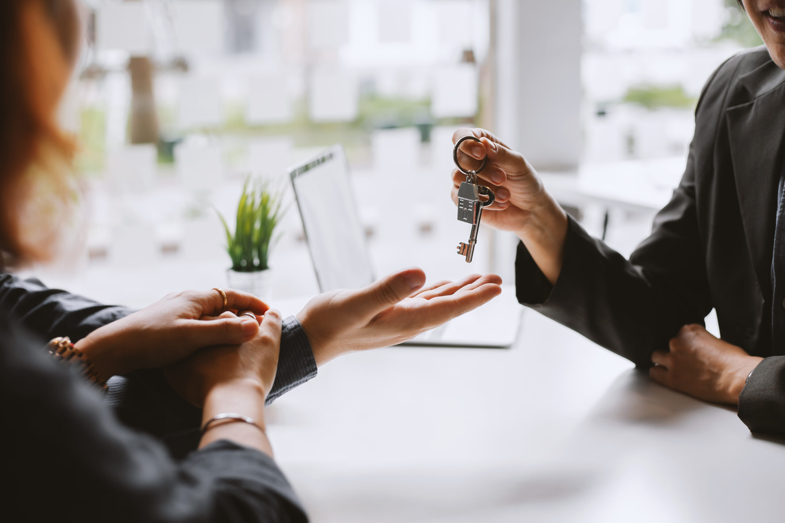 Leicester Mortgage Adviser giving house key to the client after signing the contract. Mortgage advice concept.